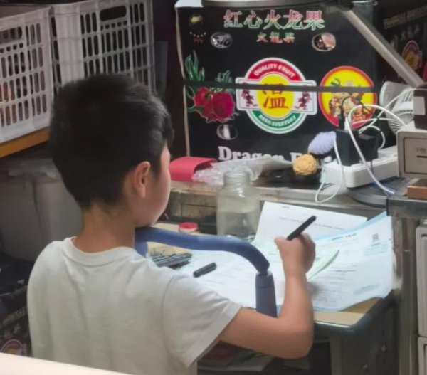 百家乐Android/通用版APP最新版 武汉闹市生果摊一小学生背对东谈主群专注写功课，四周东谈主声烦闷他全程头齐不回